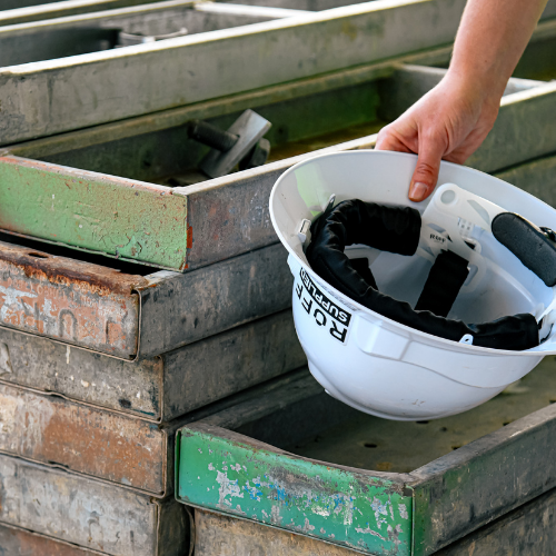Worker holding a hard hat with a fitted Ruff Supplied sweatband in their hand and placing on a stack of timber